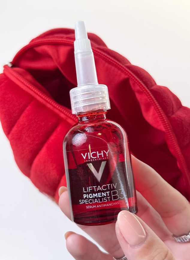 Sérum Vichy B3 segurado em frente a uma nécessaire vermelha