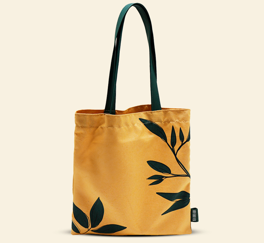 Sacola personalizada amarela com estampa de folhas e alças verdes.