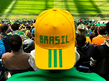 Homem com boné do Brasil assistindo jogo no estádio