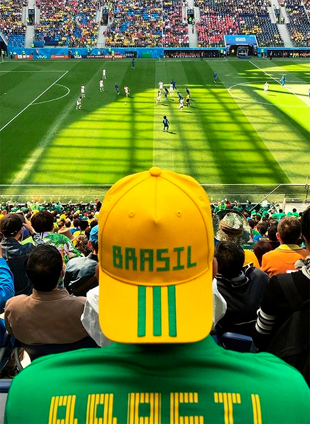 Homem com boné do Brasil assistindo jogo no estádio