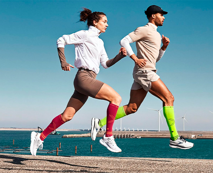 homem-mulher-correndo-corrida-esporte-meias-compressao-atividade-fisica-ao-ar-livre-mar